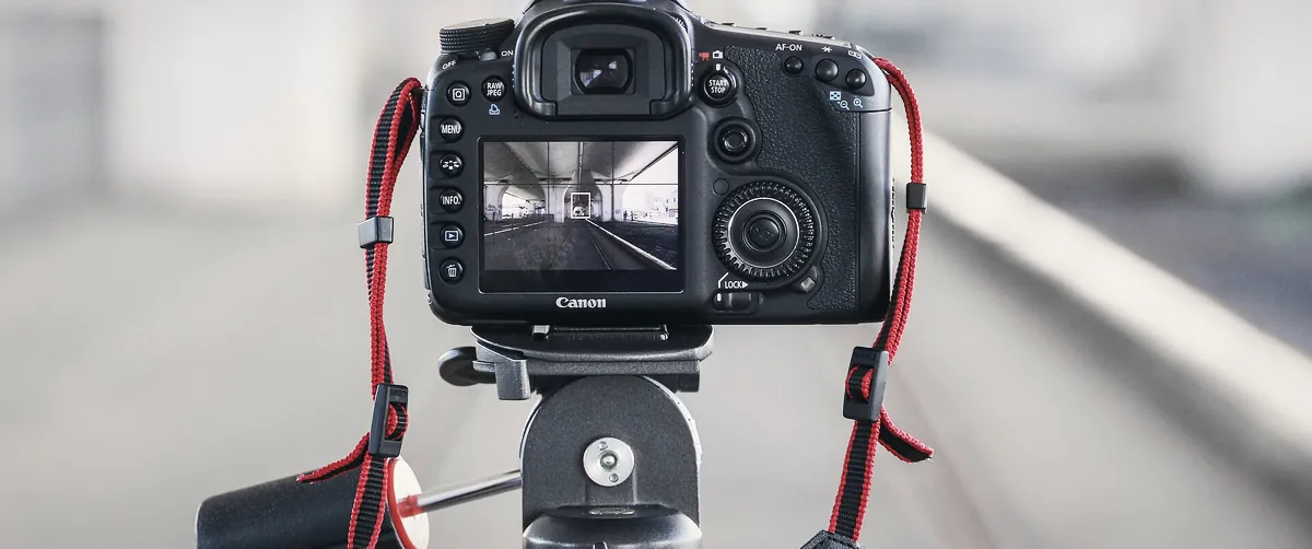 A camera on a tripod set up on a city street at dusk