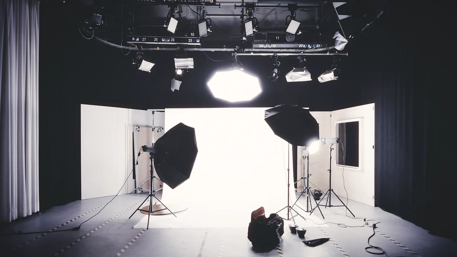 A photo studio with softboxes and lights rigged around a white backdrop