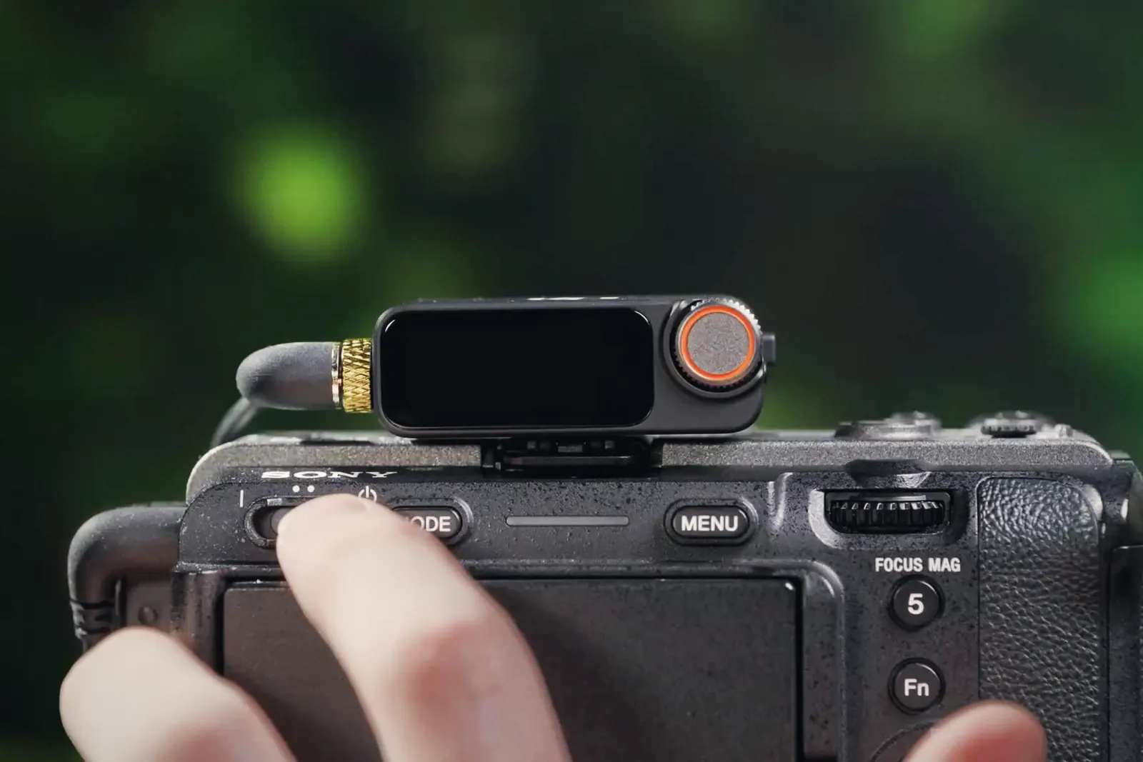 A DJI Mic 3 receiver mounted in the hot shoe of a Sony mirrorless camera, connected with a 3.5 mm cable