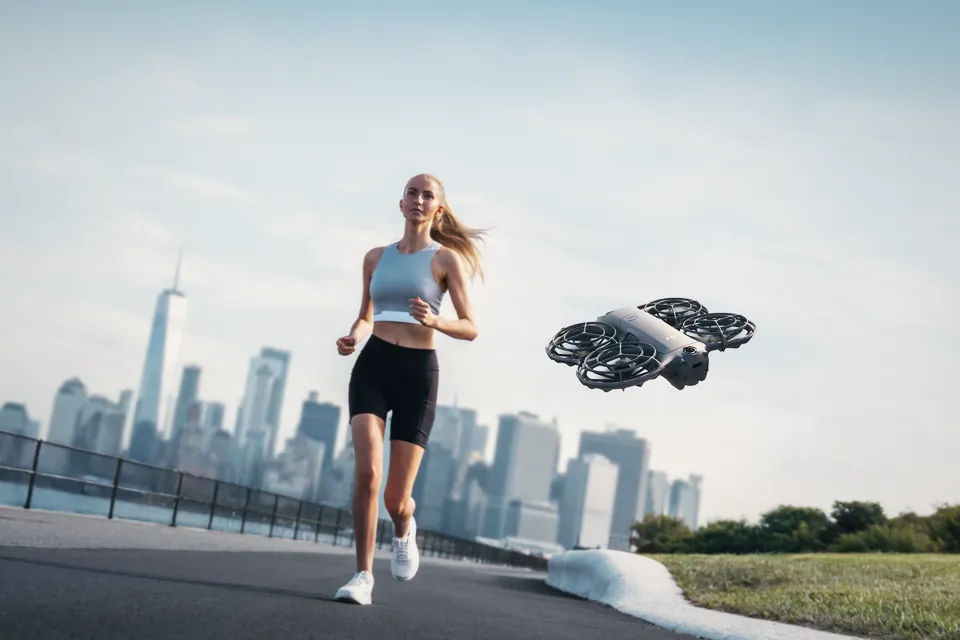 The DJI Neo 2 following a runner along a waterfront path, with the New York skyline behind