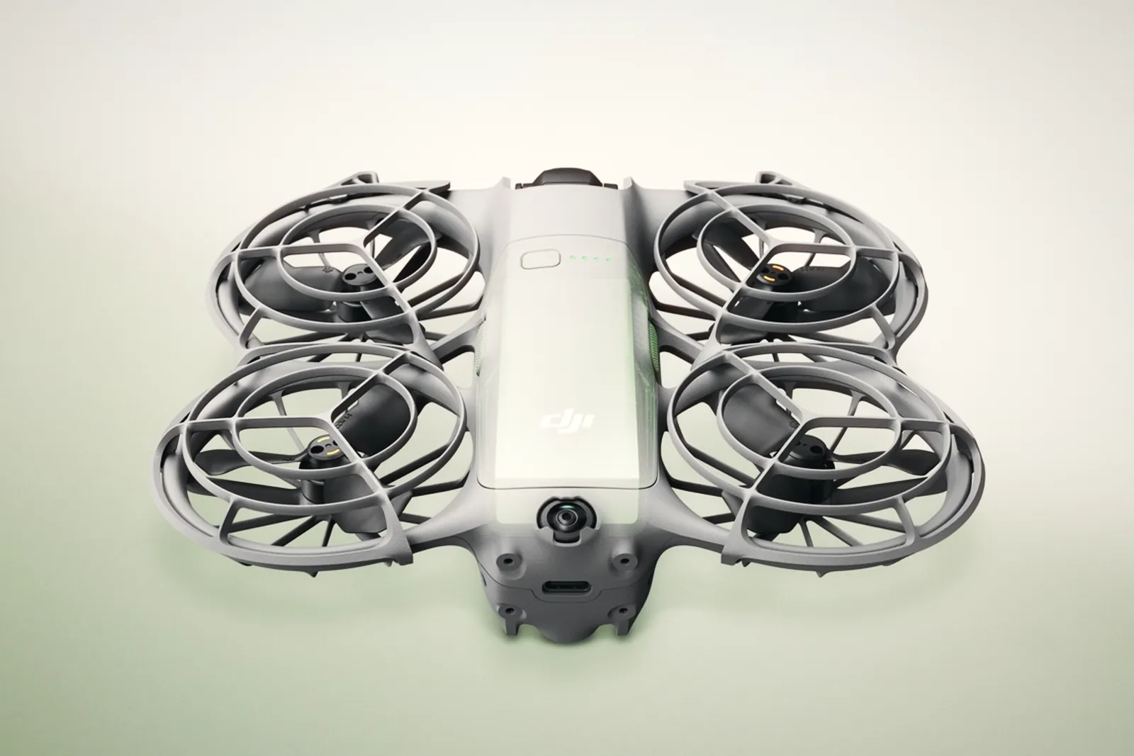 The DJI Neo 2 from above, with its four caged propellers and grey body, on a light green background