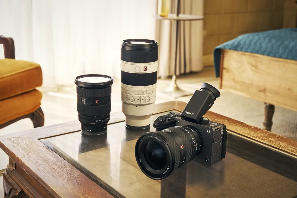 The Sony FX5 with a G Master zoom and the DVF-EL1 viewfinder on a glass coffee table, next to two more Sony lenses, in a sunlit living room