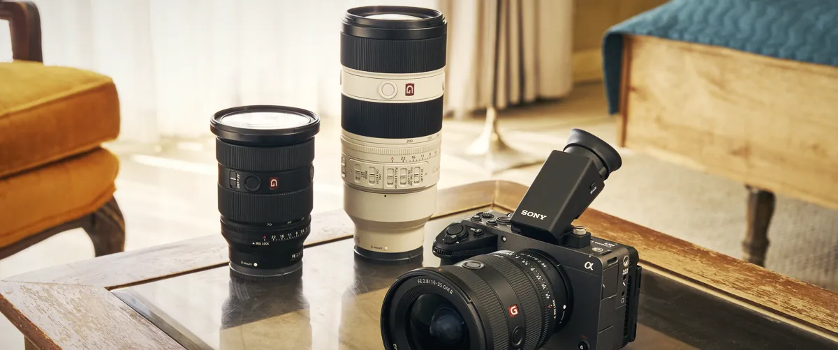 The Sony FX5 with a G Master zoom and the DVF-EL1 viewfinder on a glass coffee table, next to two more Sony lenses, in a sunlit living room